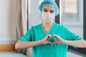 Masked nurse forming a heart with her hands