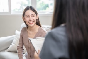 Smiling young woman on a couch next to a medical professional